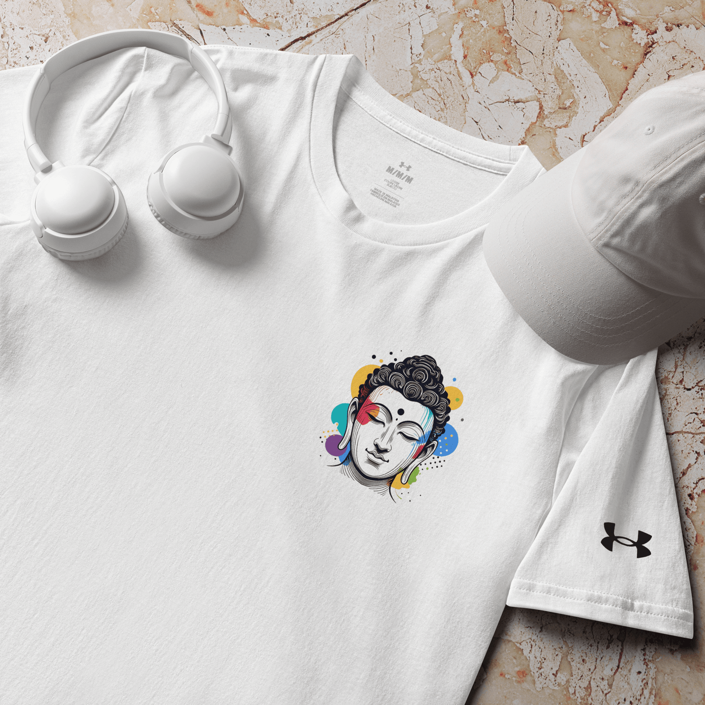 White Under Armour t-shirt featuring a colorful Buddha design, paired with headphones and a cap, perfect for mindfulness and meditation.